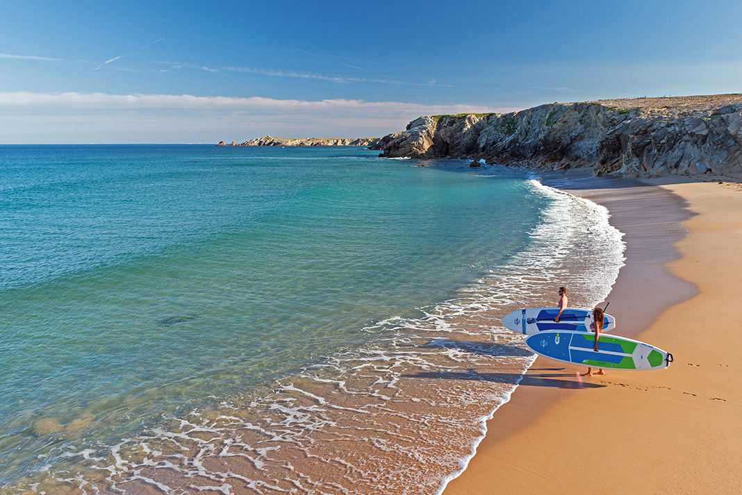 two people stand on a sandy beach holding paddleboards from BIC SUP