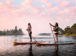 Two women paddling paddleboards on a lake