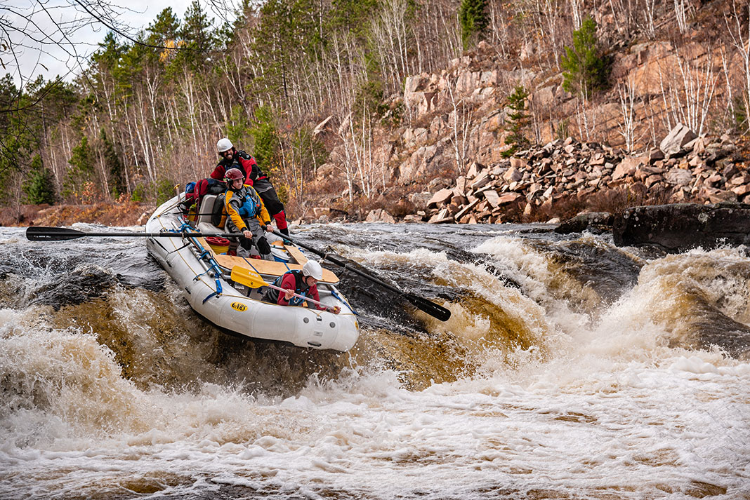 a group of whitewater rafters go over some rapids
