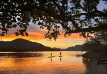 two people paddleboarding while silhouetted by the sunset at Loch Lomond, Scotland