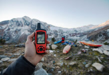 person holds up a Garmin handheld GPS at a mountainous kayak location