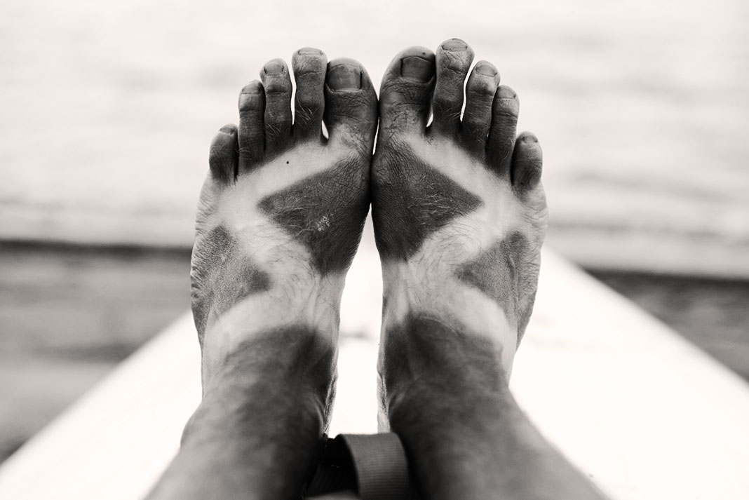 a paddler's deeply suntanned feet in black and white