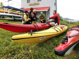 People sitting on grass beside kayaks