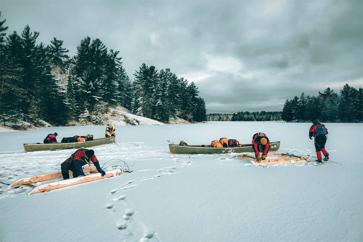 a group guided by Lure of the North takes part in canoe sledding on a frozen lake