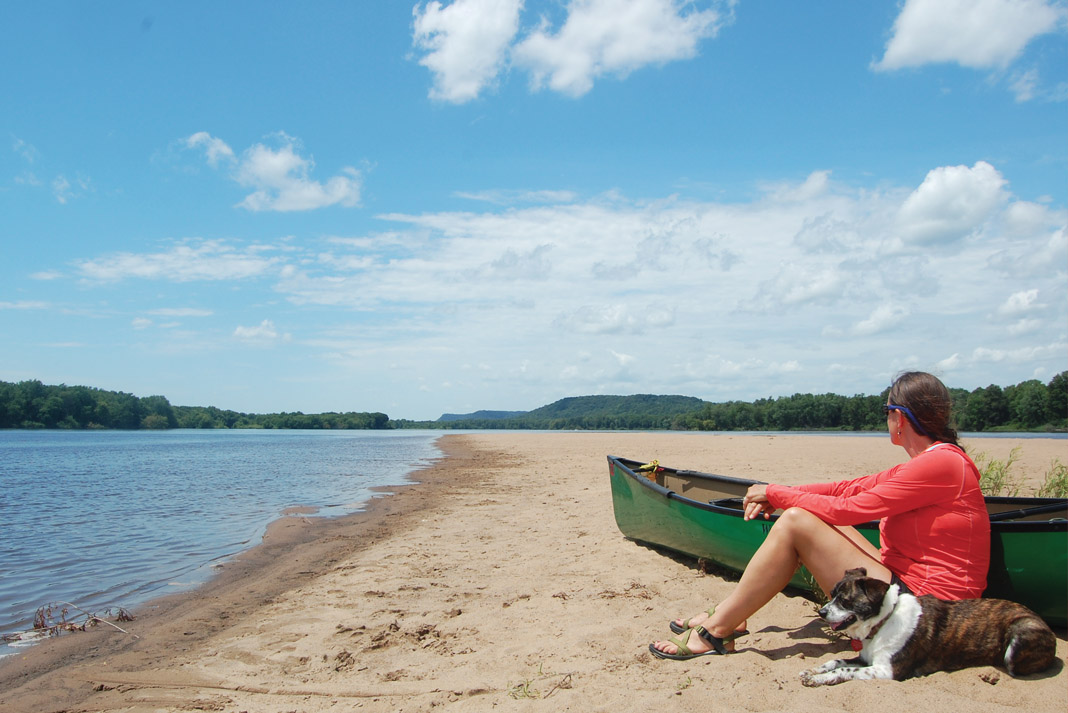 woman takes a break with her dog while canoeing the lower Wisconsin River