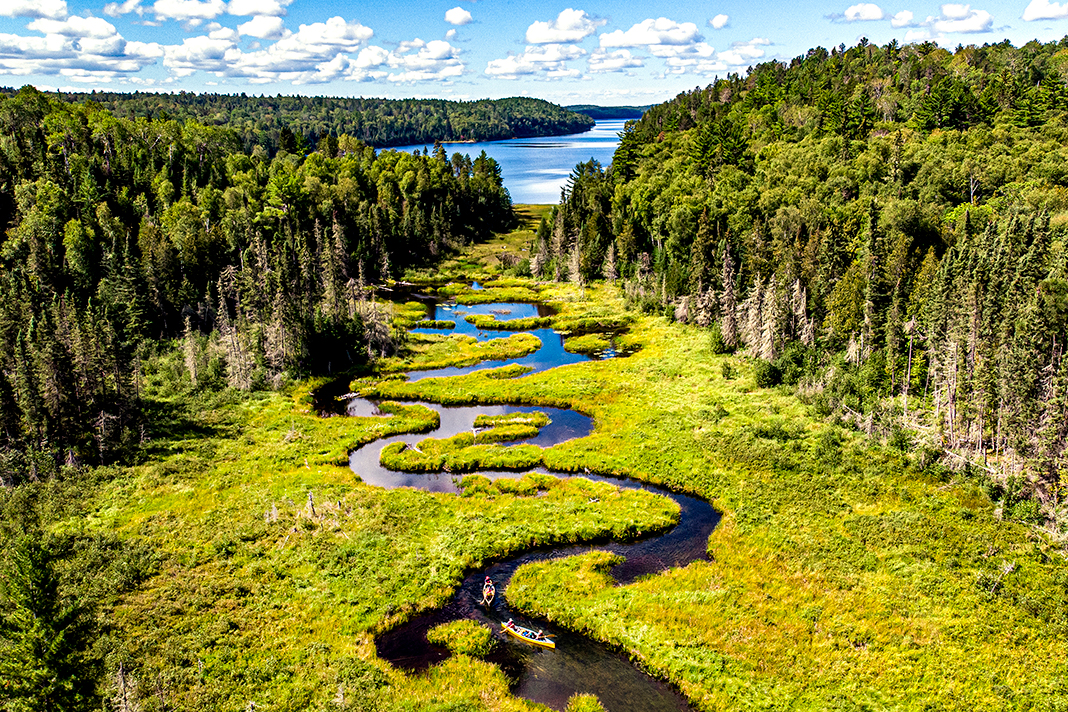 Creek running through a wetland with lake in the background.