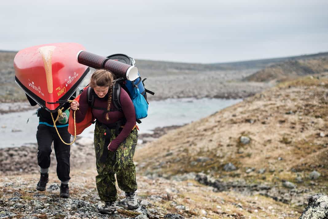two women portaging heavy canoe