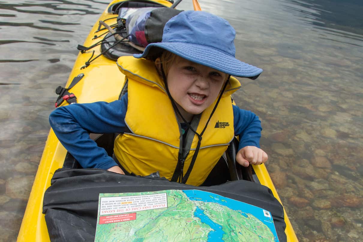 kid poses in a kayak with map