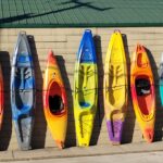 group of kayaks of different sizes lined up outside a building