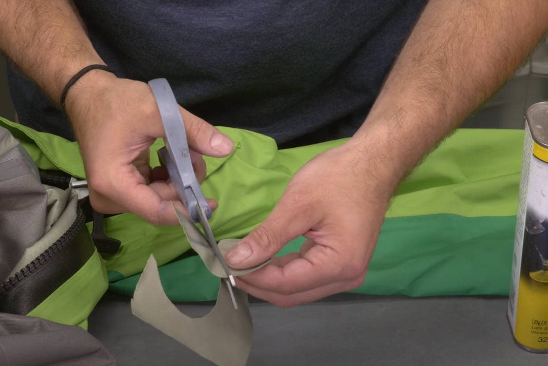 Man cuts patch to use to repair drysuit leak